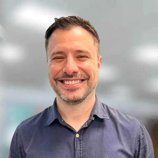 Jonny Rebello sorridente, novo líder comercial da NETZSCH, com fundo desfocado em ambiente corporativo moderno.