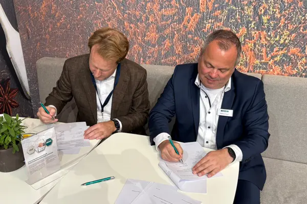 Two business professionals signing partnership documents at a table, highlighting NETZSCH's strategic collaboration in food technology.
