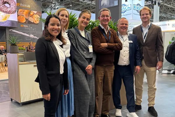 Group of six professionals smiling at a trade show booth, highlighting NETZSCH’s strategic partnership for food and pharma innovation.