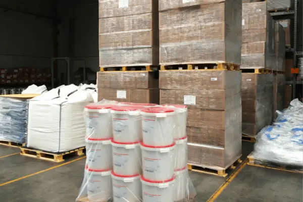 Sichere Verpackung diverser Gebinde für den Transport, einschließlich Kunststoffbehältern und Kartons, in einem Lagerraum.