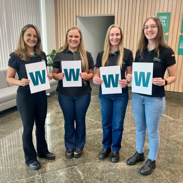 Quatre collègues féminines de NETZSCH Moagem & Dispersão au Brésil brandissent des pancartes avec la lettre "W" pour célébrer la Journée internationale de la femme.