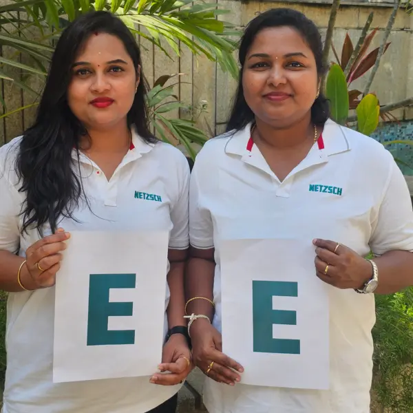 Zwei weibliche Kolleginnen von NETZSCH India präsentieren stolz den Buchstaben "E" im Freien, um Vielfalt und Stärke von Frauen zu feiern.
