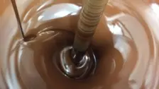 Rich, smooth milk chocolate being refined and mixed in high-efficiency confectionery processing equipment.